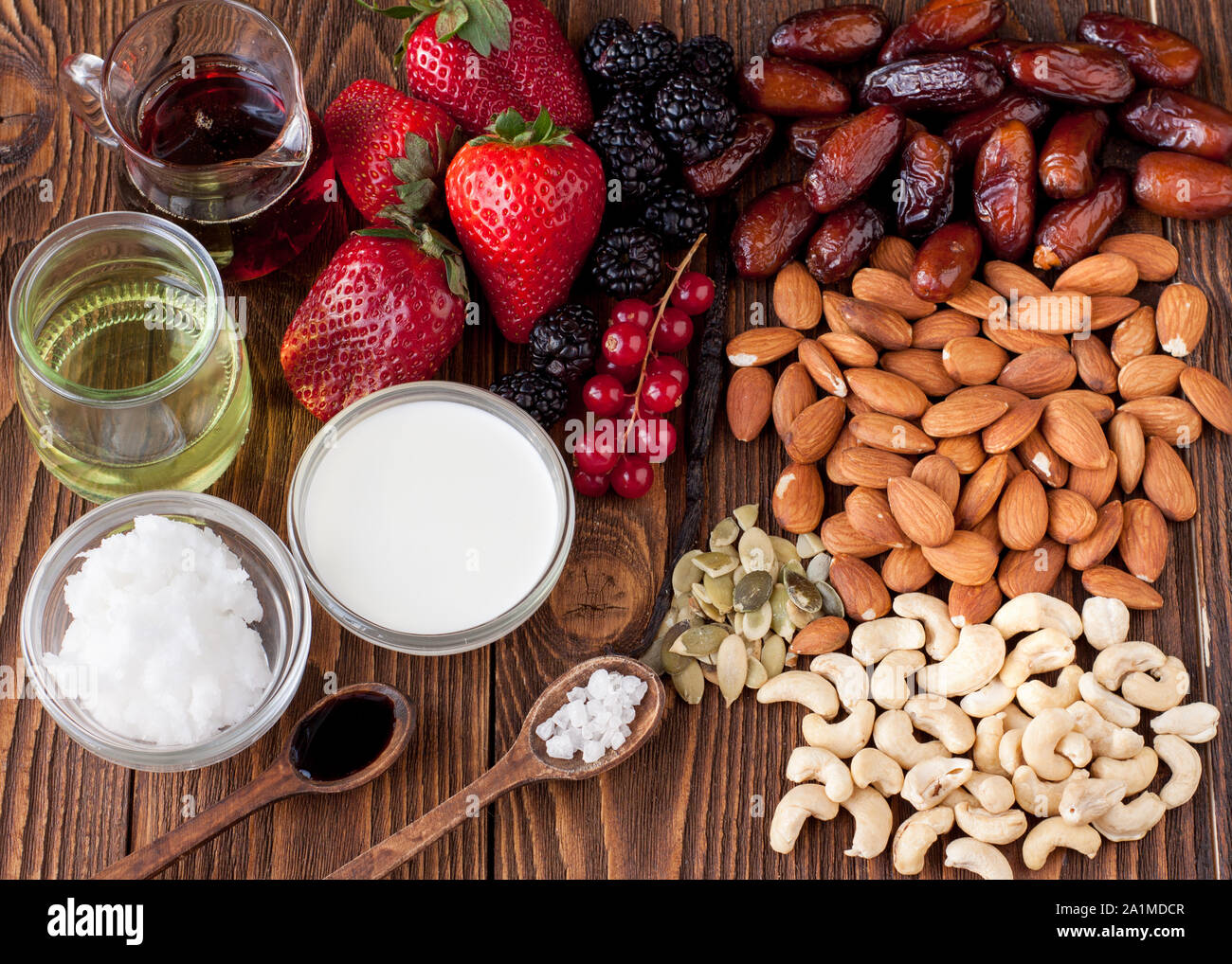 Bacche, dadi, il latte di cocco e il burro, sirup di acero. Ingredienti per materie vegan cheesecake con sirup di caramello e frutti di bosco freschi preparazione Foto Stock
