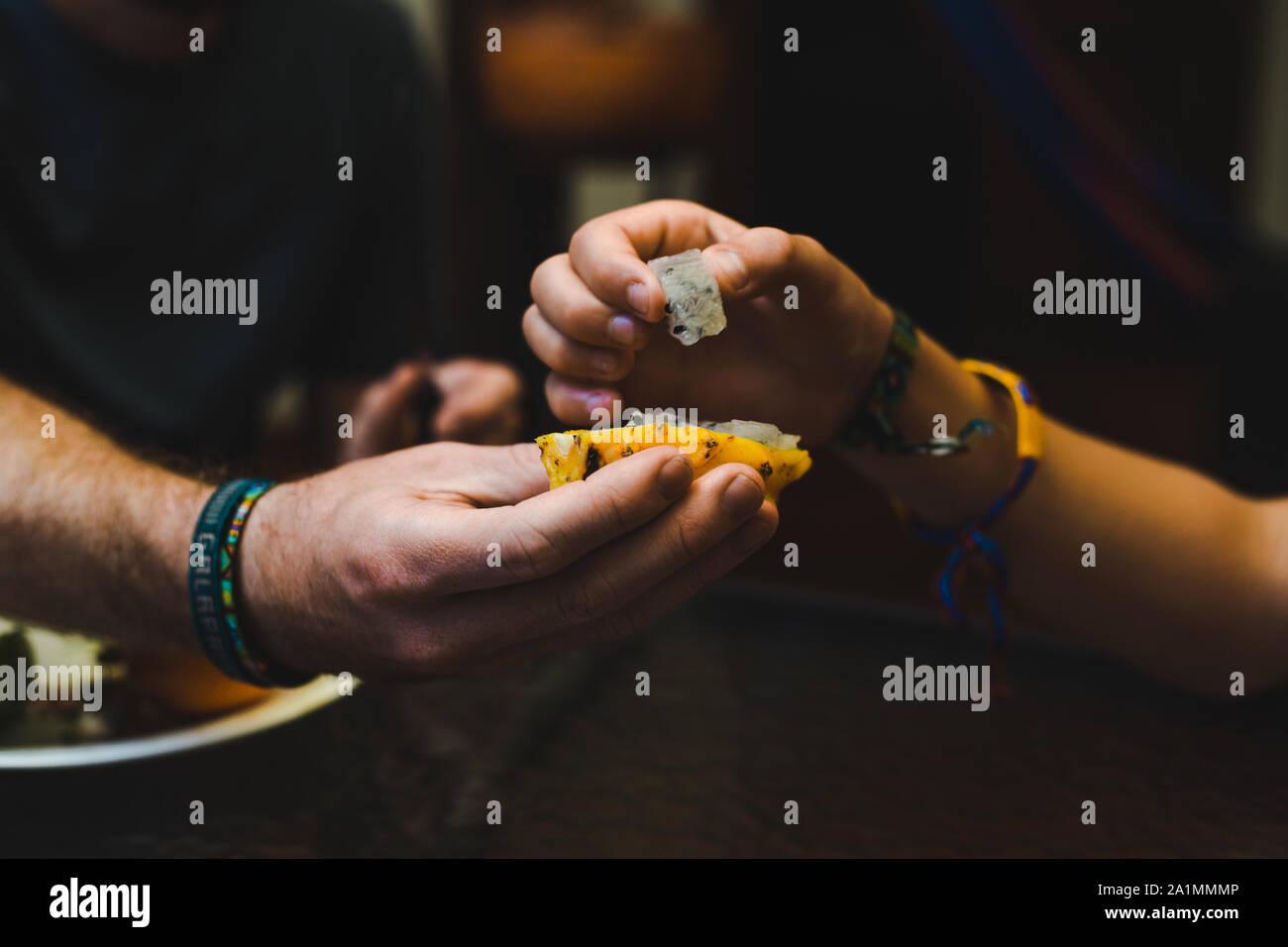 Close-up di mani di 2 turisti su un cibo tour di degustazione cercando dragon pitaya frutto per la prima volta in un mercato della frutta in Colombia Foto Stock