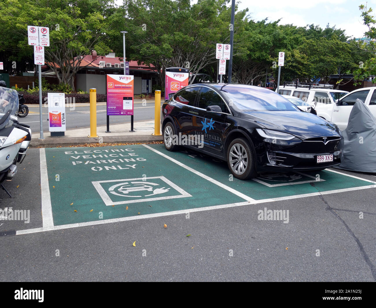 Una vista generale di una doppia EV stazione di parcheggio con una Tesla essendo caricato in Tropical North Queensland Foto Stock