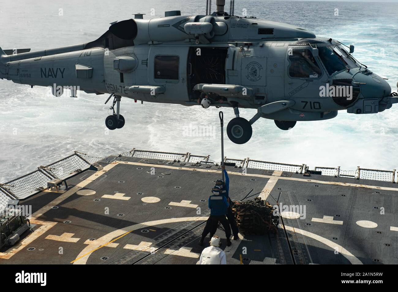 190918-N-MD802-1003 OCEANO ATLANTICO (sett. 18, 2019) Boatswain compagno del marinaio Justin Liebl e marinaio Orlando Rosales tentativo di collegare un telecomando per un gancio su un MH60R Sea Hawk elicottero, attaccata la "fieri guerrieri" di elicottero sciopero marittimo Squadron (HSM) 72 durante un rifornimento verticale a bordo del Arleigh Burke-class guidato-missile destroyer USS Farragut (DDG 99) mentre in transito attraverso l'Oceano Atlantico, Sett. 18. Farragut è operativo in Atlantico a sostegno di operazioni navali per mantenere la stabilità di marittimi e di sicurezza al fine di garantire l'accesso, dissuadere aggressione e difendere il allie NEGLI STATI UNITI Foto Stock
