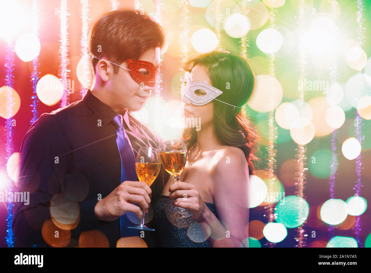 Coppia giovane per celebrare il nuovo anno e di bere champagne su masquerade party Foto Stock