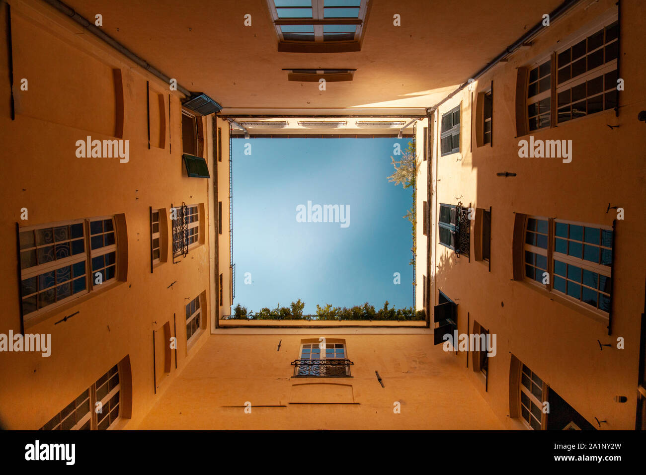 Concetto di quarantena. Vista del cielo blu dal basso verso l'alto all'interno di un piccolo cortile di una vecchia casa in Italia Foto Stock