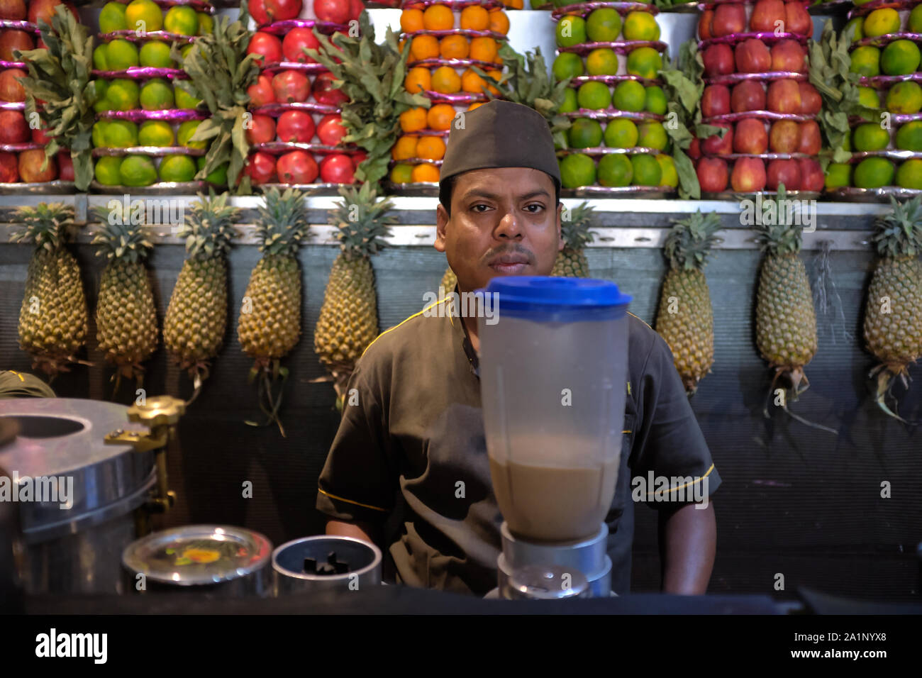 Un dipendente di Badshah bevanda fredda House, Mumbai, India, un ben noto succo di frutta & gelateria, rendendo un Chikoo (Sapodilla, Sapota) frullato Foto Stock