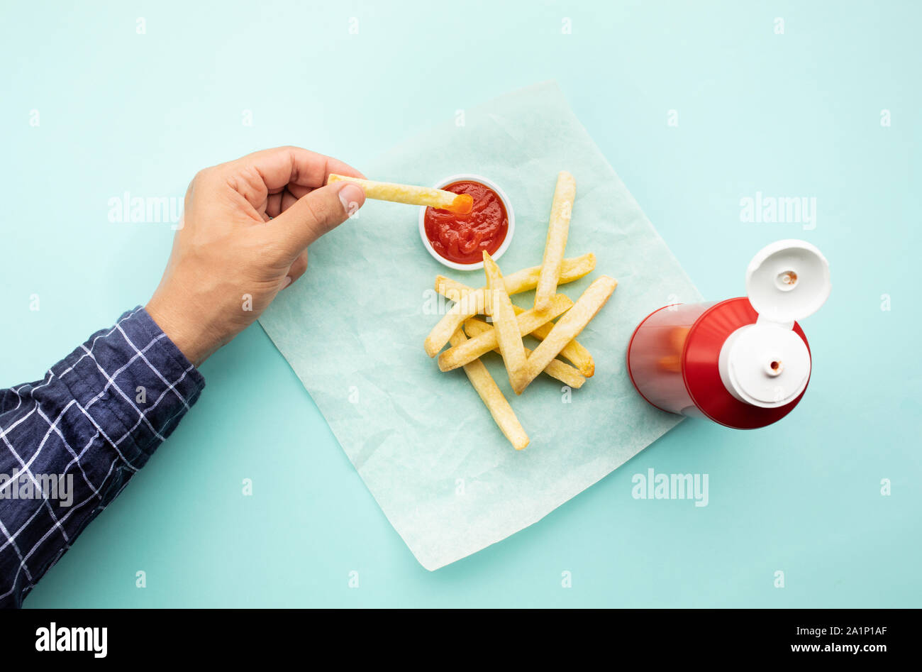 Vista superiore della youngman piace mangiare con patatine fritte e immergendo la salsa di pomodoro ( ketchup ) sul colore di sfondo della tabella.fast food e concetti sani ide Foto Stock