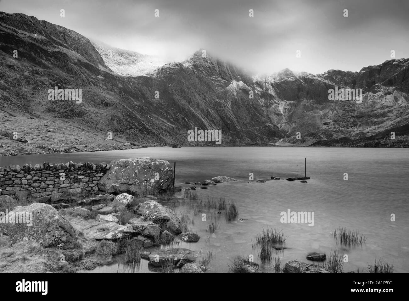 Incredibile drammatico paesaggio invernale immagine del Llyn Idwal e nevato Glyders Mountain Range in Snowdonia in bianco e nero Foto Stock