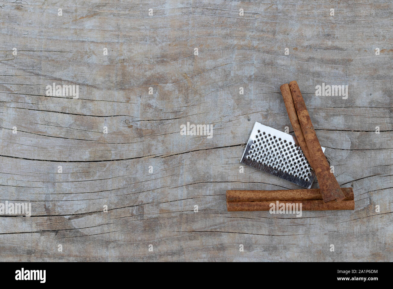 Due bastoncini di cannella e mini grattugia su uno sfondo di legno Foto Stock