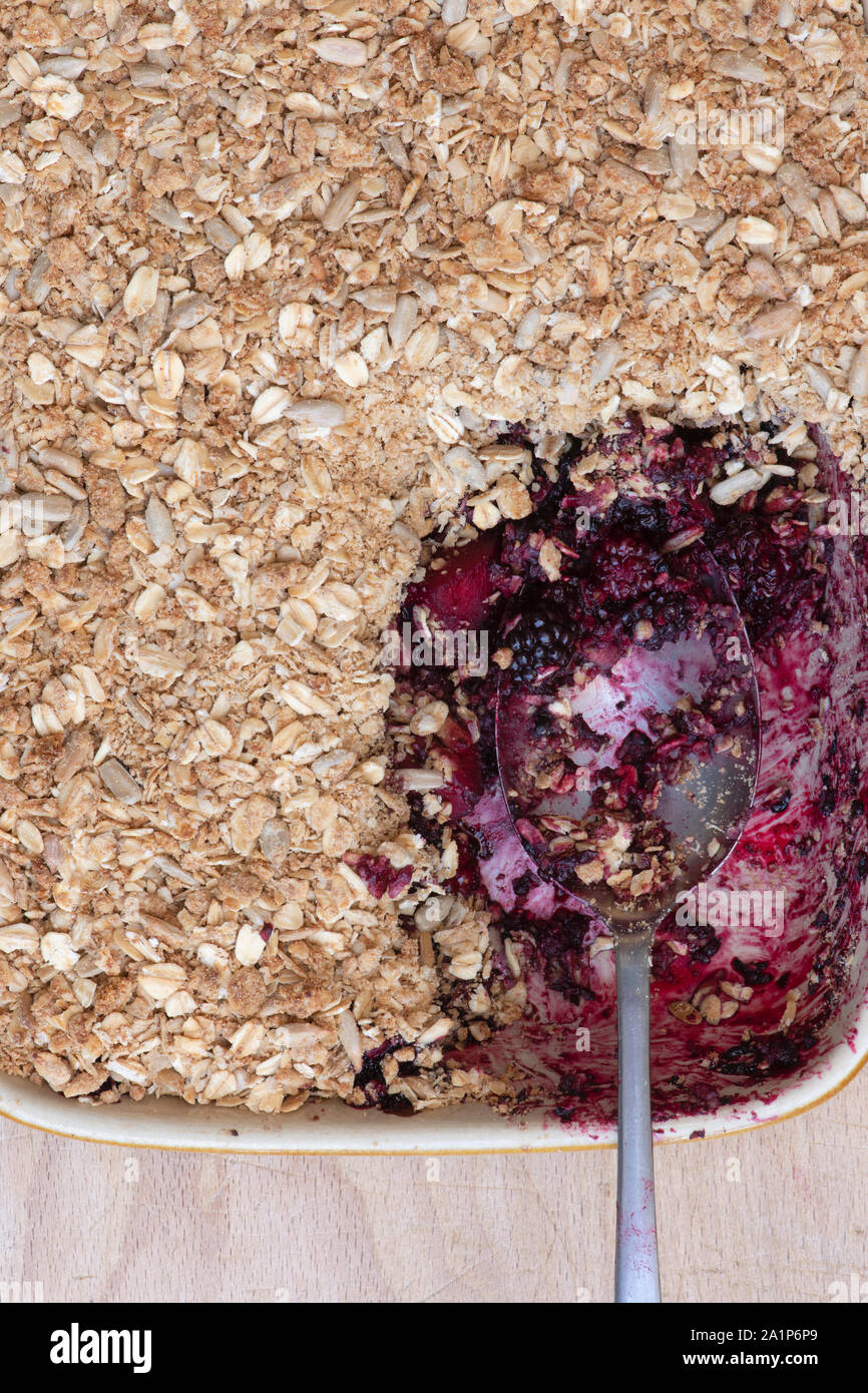 In casa di Blackberry e apple crumble con un cucchiaio. Oat organico e seme sgretolarsi con foraged more e mele Foto Stock