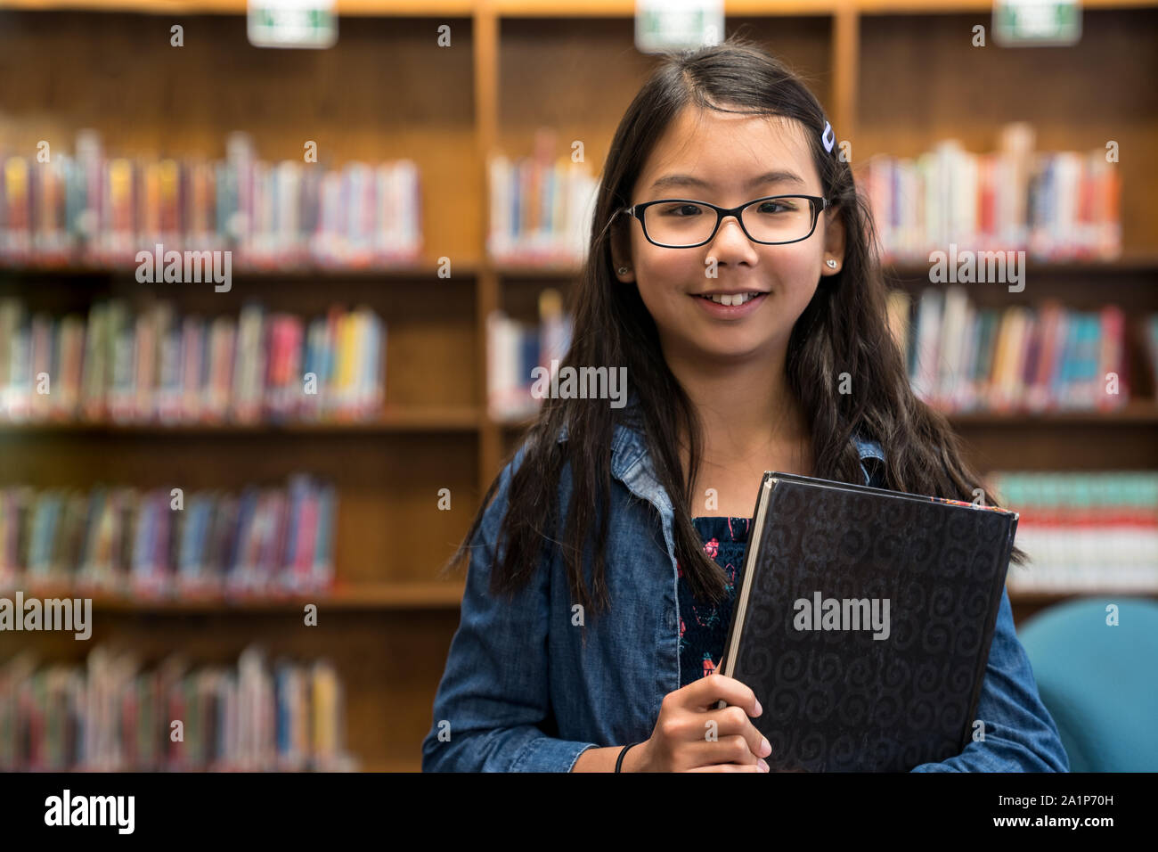 Asian ragazza adolescente con gli occhiali in biblioteca scolastica Foto Stock