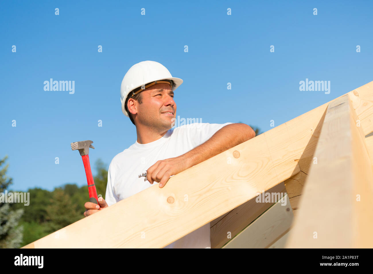 Giovane artigiano lavorando sodo per costruire il tetto di una casa nuova Foto Stock