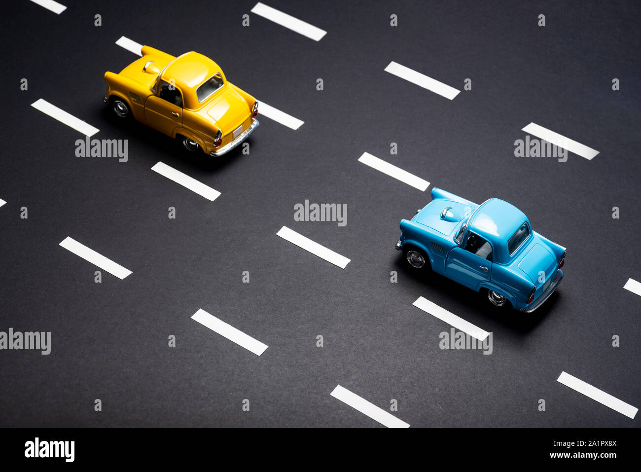 Due automobili giocattolo sulla strada una dopo l'altra. Uno è blu è colorata in giallo. Foto Stock