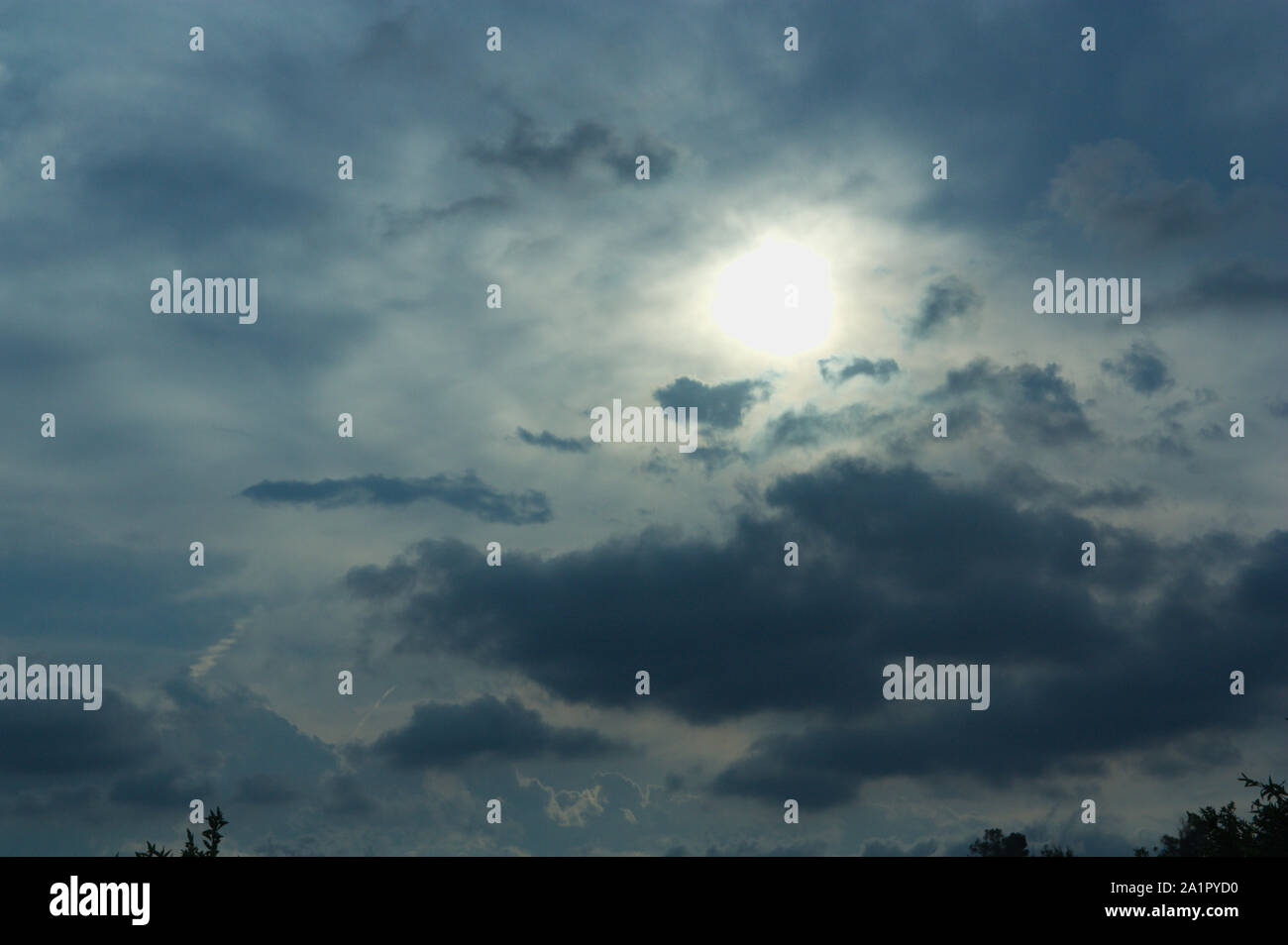 La luce del sole penetra attraverso nuvole temporalesche lasciando un buio luce nel cielo Foto Stock