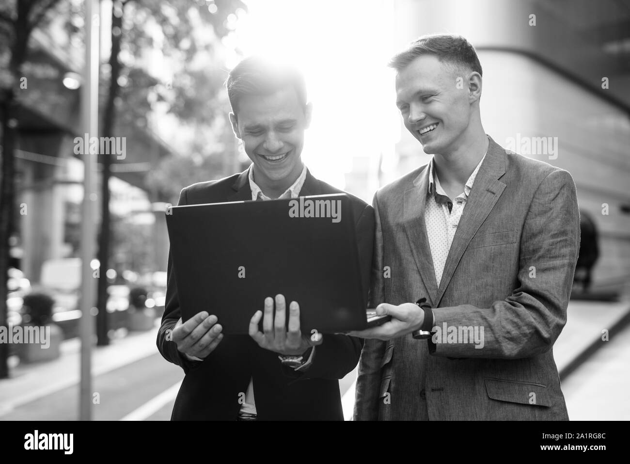 Due imprenditori che lavorano insieme al di fuori con computer portatile Foto Stock Due imprenditori che lavorano insieme al di fuori con computer portatile Foto Stock