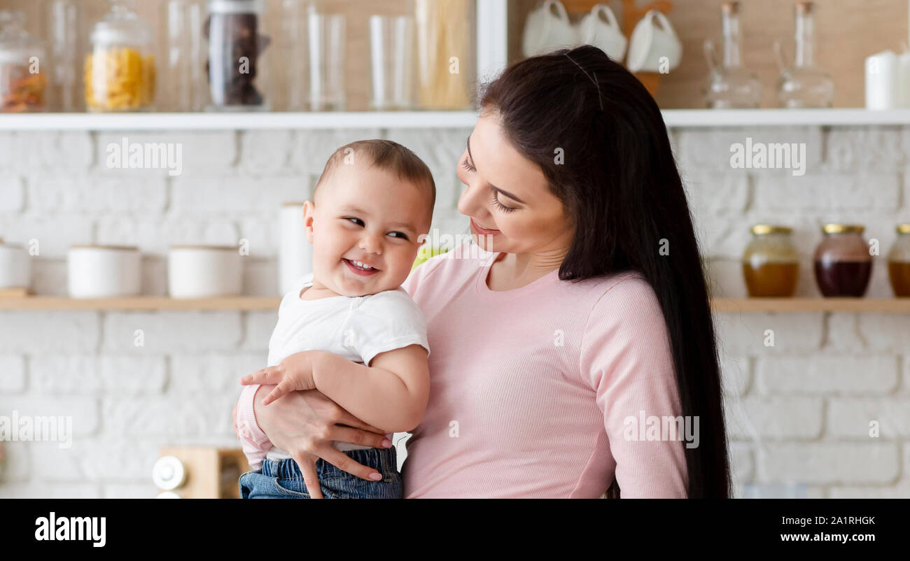 Allegro madre tenendo le sue Laughing baby in cucina Foto Stock