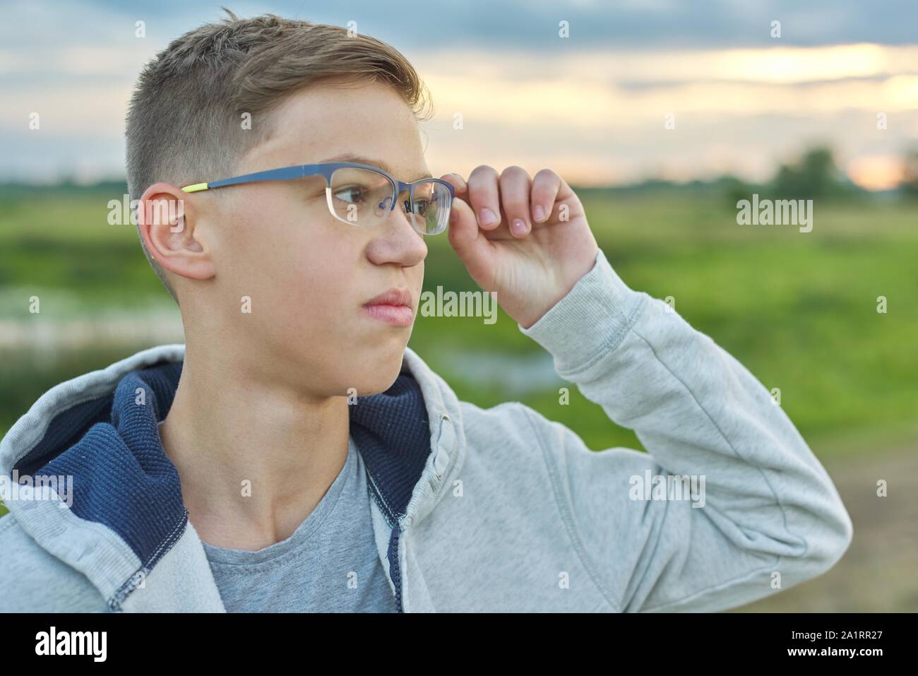 Close-up ritratto all'aperto del ragazzo di 14 anni con gli occhiali. Teen  guarda nel mantenimento della distanza i suoi occhiali Foto stock - Alamy