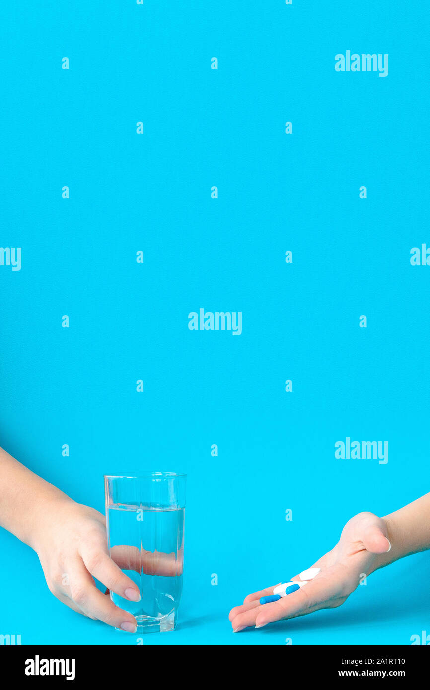 Mani pillole e acqua su uno sfondo blu Foto Stock