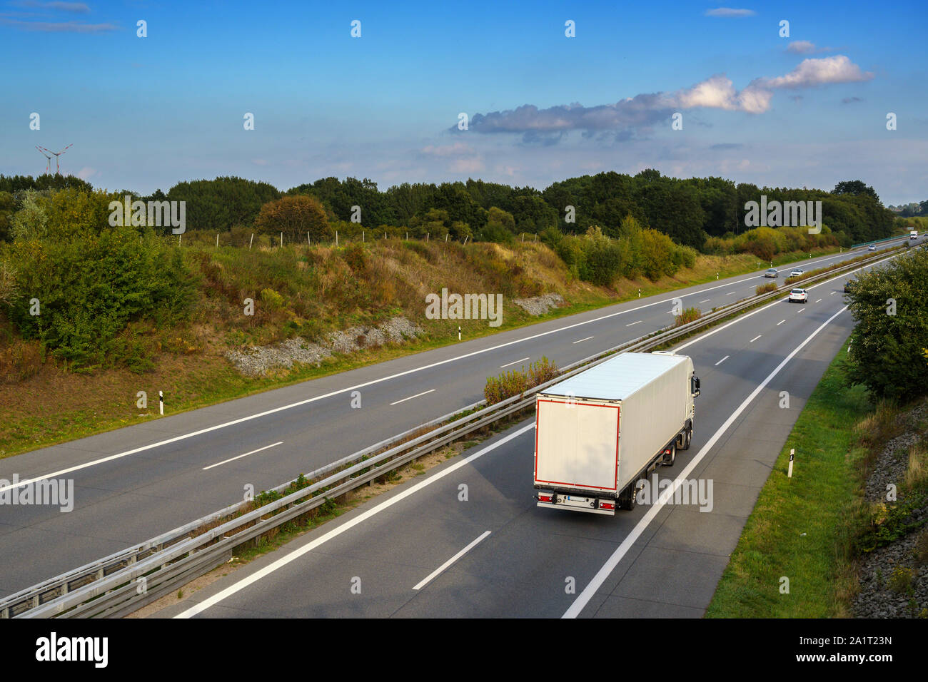 Carrello bianco è la guida su autostrada attraverso il paesaggio di campagna sotto un cielo blu con nuvole, trasporti e ambiente concetto, spazio di copia Foto Stock