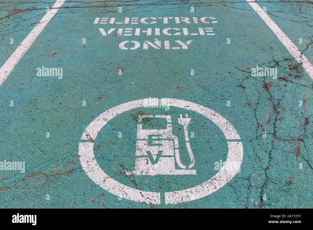 Posto di parcheggio della stazione di carica del veicolo elettrico (EV) con icona e testo "solo veicolo elettrico" su pavimentazione verniciata di verde. Foto Stock