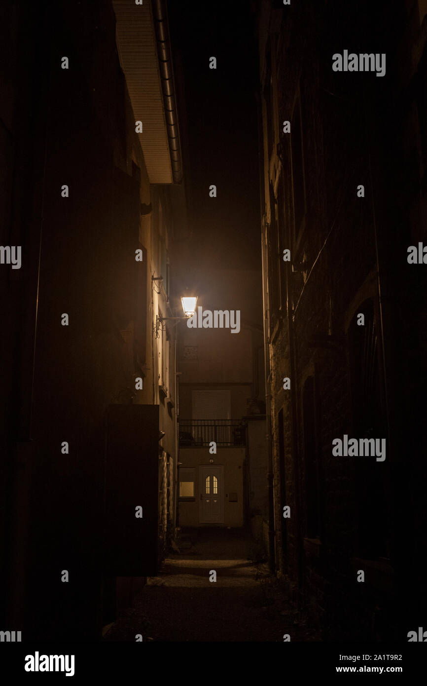 Dark street, una situazione di impasse in un vicolo cieco back street, con una fioca luce arancione, circondato da edifici residenziali in un tipico centro storico di Francia Foto Stock