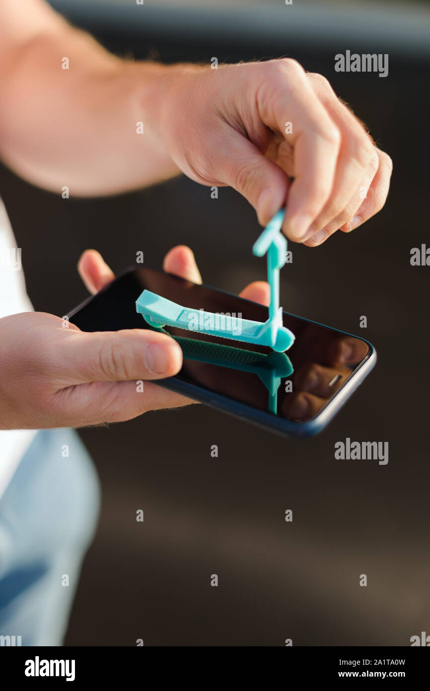Un uomo tiene nelle sue mani una miniatura del modello di scooter su un display del telefono, eco-friendly Foto Stock