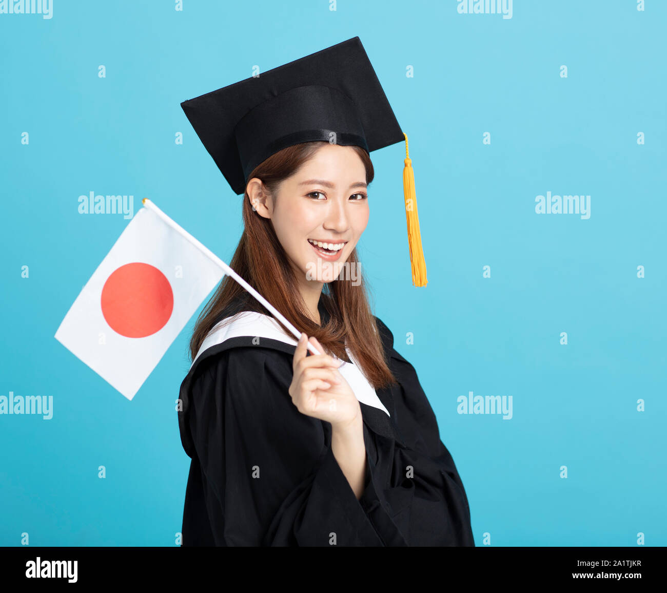 Felice femmina asiatica studente laureato che mostra la bandiera del Giappone Foto Stock