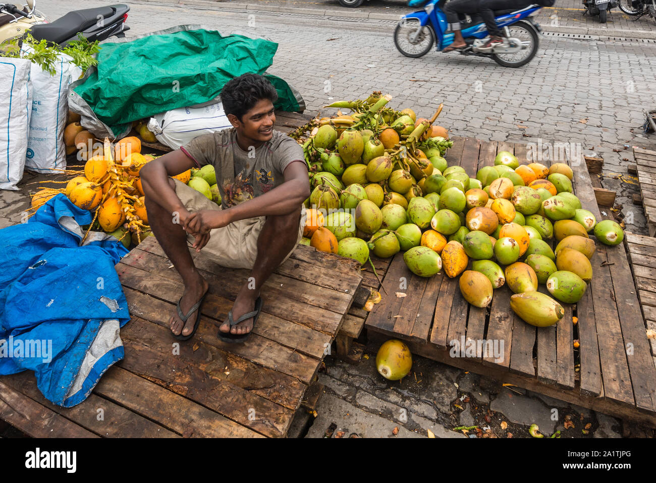 Maschio, Maldive - Novembre 16, 2017: il fornitore vende noci di cocco sulla strada a nuvoloso meteo maschio, la capitale delle Maldive. Maschio mercato locale delle Maldive. Foto Stock