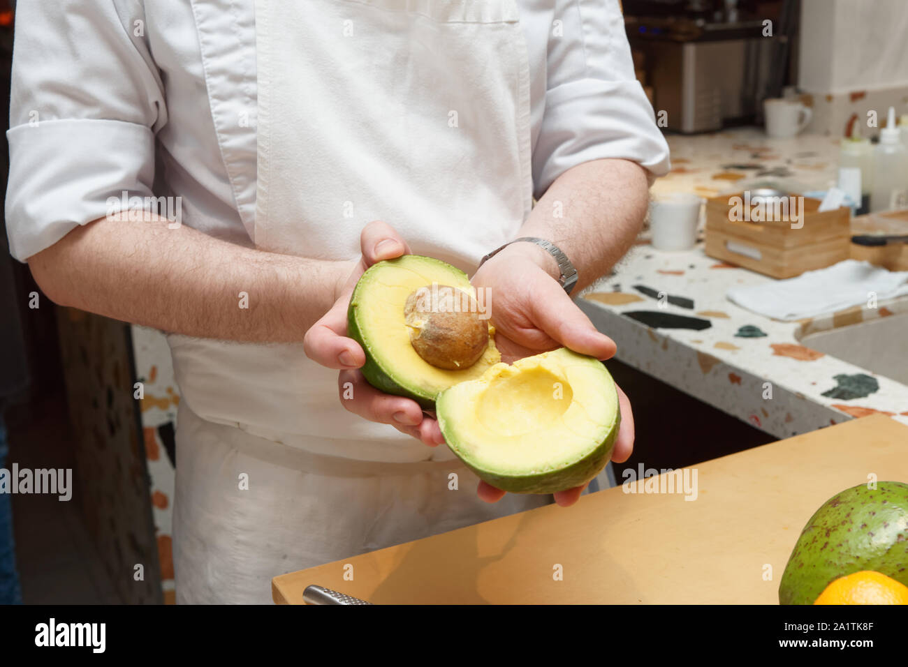 Lo chef è che mostra un avocado tagliato in due pezzi, all'interno della pietra Foto Stock