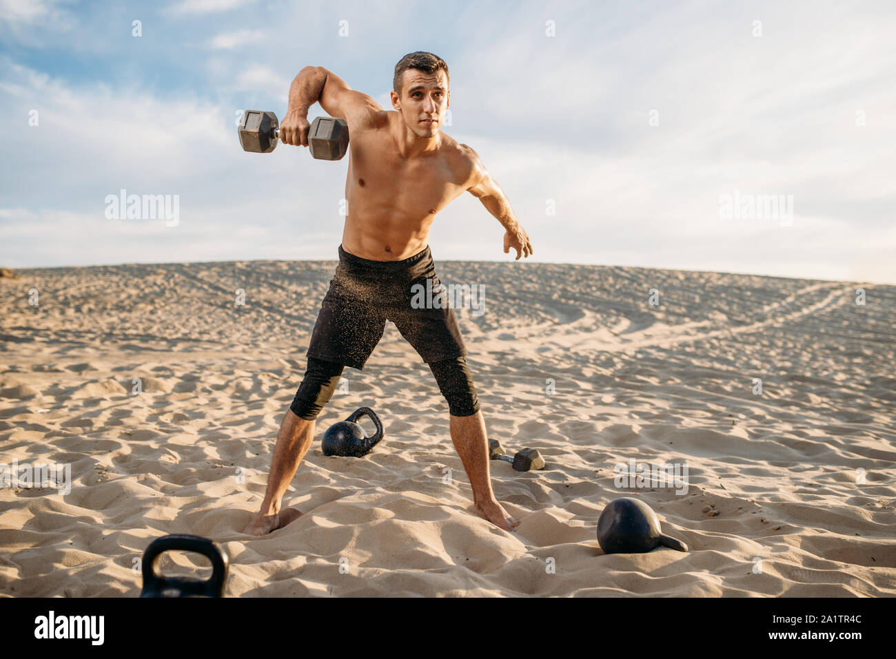Sportivo fare esercizio con pesi nel deserto Foto Stock