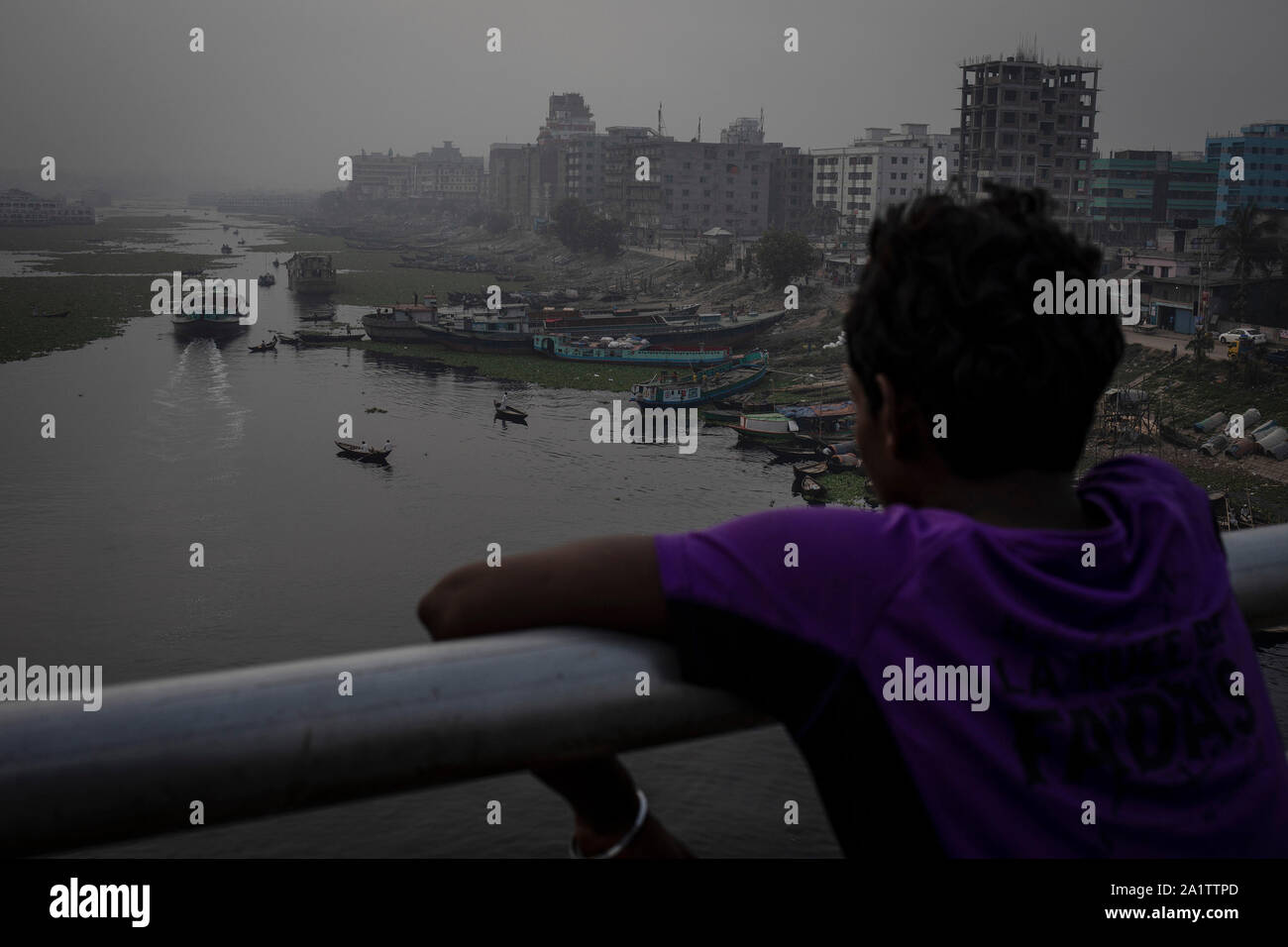 Un ragazzo guarda al fortemente inquinato fiume Buriganga da un ponte nella capitale Dhaka, Bangladesh, 27 aprile 2019. Foto Stock