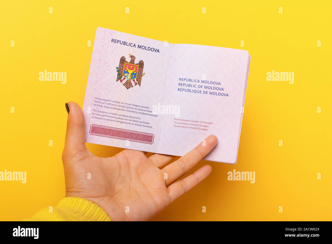 Aprire il passaporto moldavo in mano su sfondo giallo Foto Stock