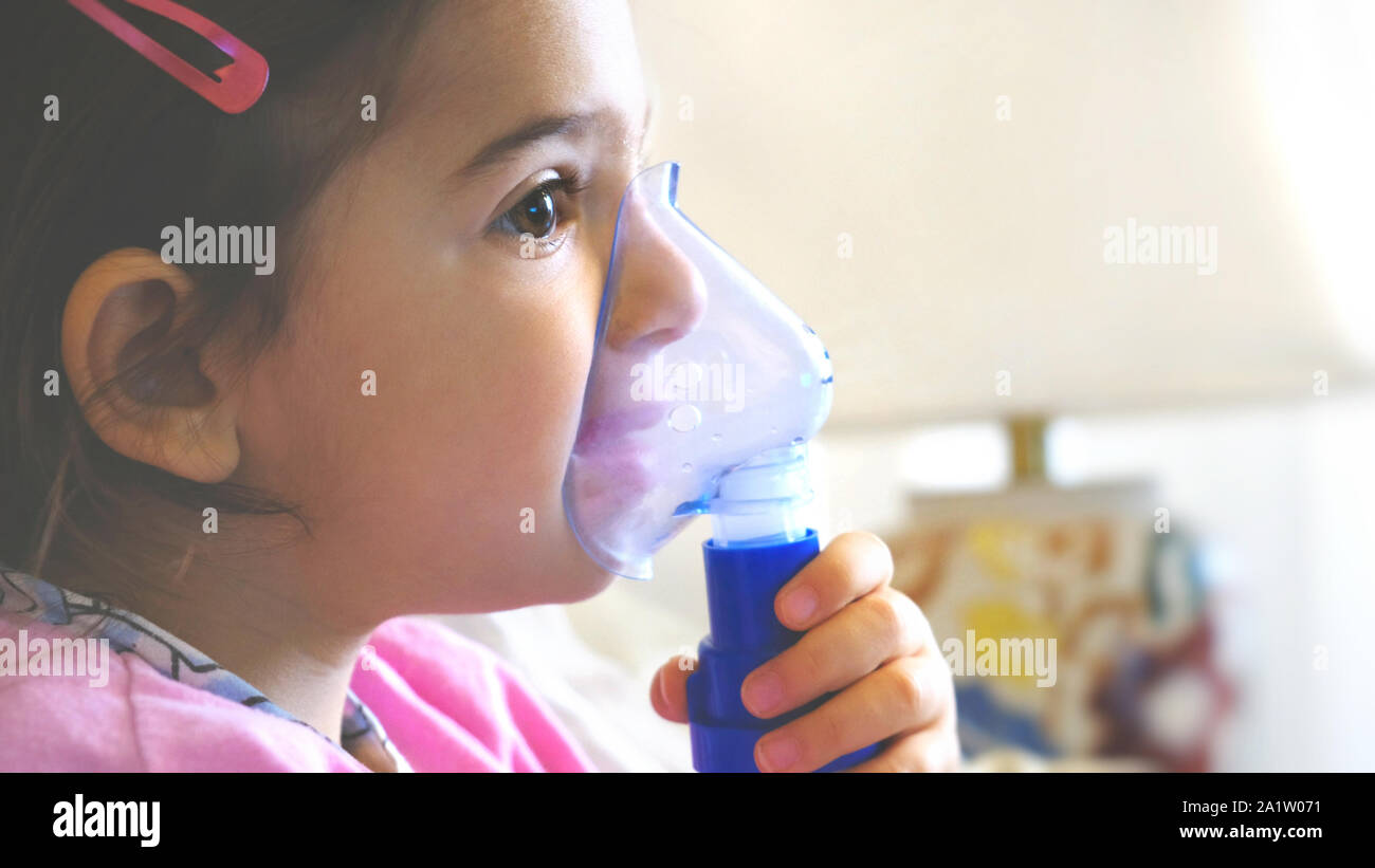 Asma infantile maschera di inalazione di malattie poco bambina con flu id aerosol facendo in modo indipendente Foto Stock