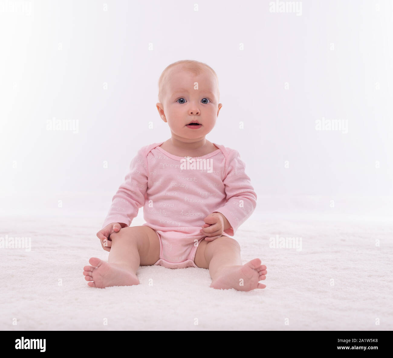 Bambina piccola su un tappeto bianco in una stanza luminosa. Foto Stock