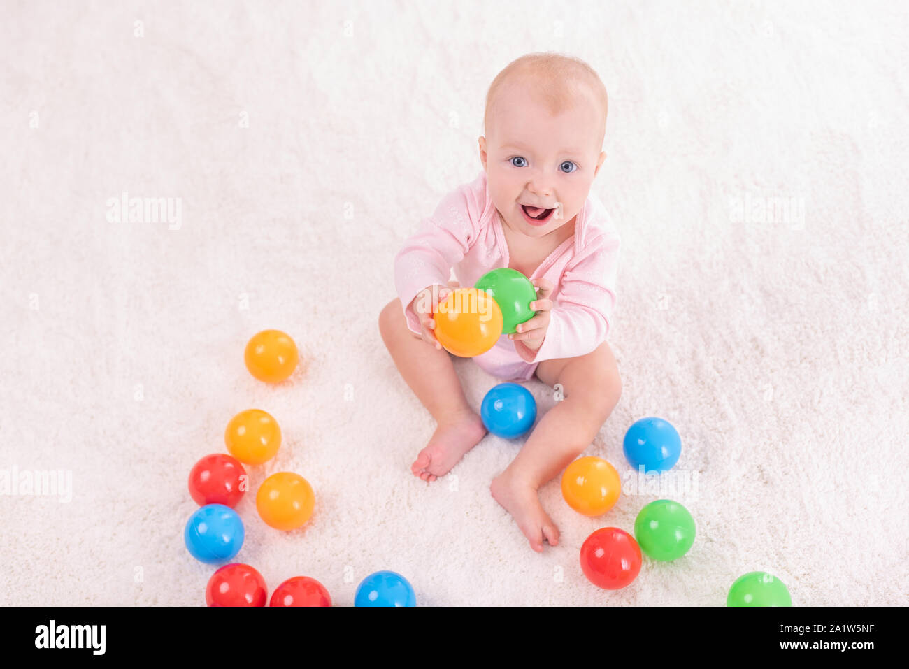 Bambina piccola su un tappeto bianco in una stanza luminosa. Foto Stock