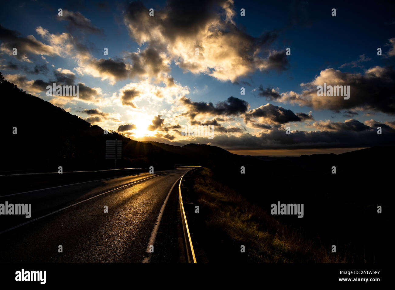 Il giallo del sole su una cloudscape sunrise paesaggio di montagna bordo stradale Foto Stock