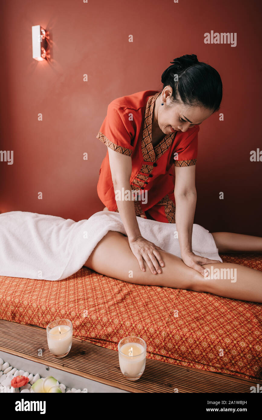 Massaggiatore asiatico facendo massaggio ai piedi per donna in spa salone Foto Stock