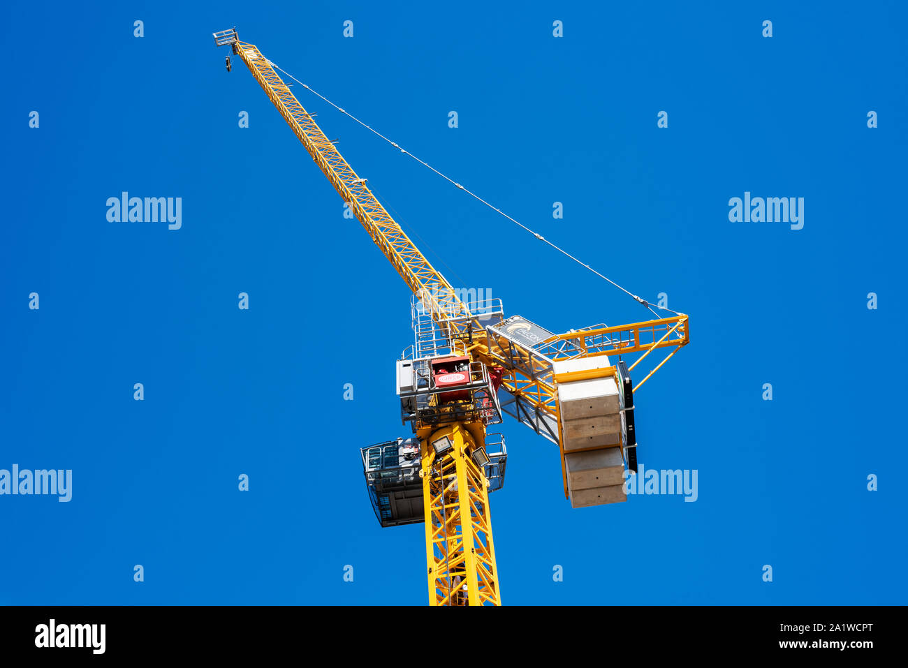 Giallo gru a torre in contrasto contro il cielo blu, sfondo mostrante montante, unità girevole, pesi, braccio, braccio del contatore, il paranco, sollevare il verricello, cabina e gancio. Foto Stock