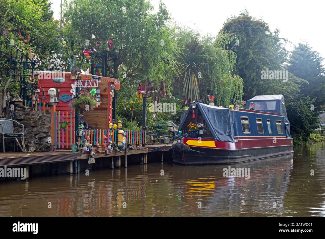 Una stretta barca o chiatta ormeggiata fino al fianco di un colorato, divertente, ormeggio sul Shropshire Union Canal in Inghilterra. Foto Stock
