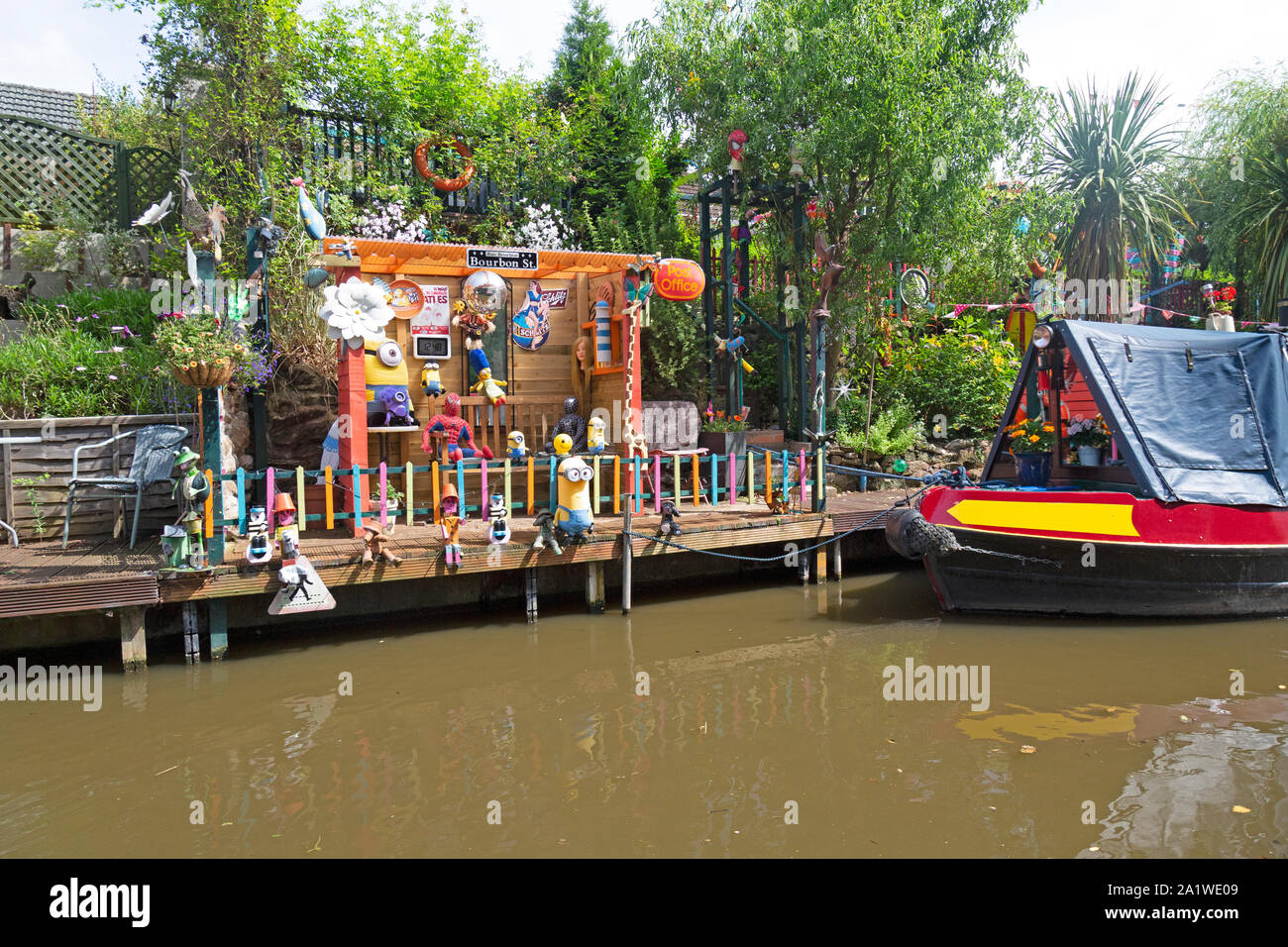 Una stretta barca o chiatta ormeggiata fino al fianco di un divertente e colorato, di ormeggio sul Shropshire Union Canal in Inghilterra. Foto Stock
