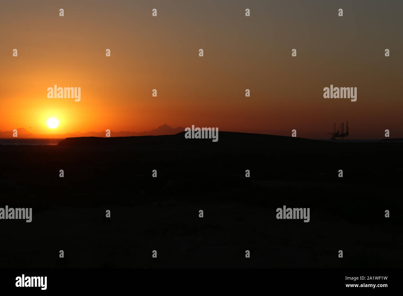 Tramonto sul mare con la silhouette di un carro di perforazione in olio Foto Stock