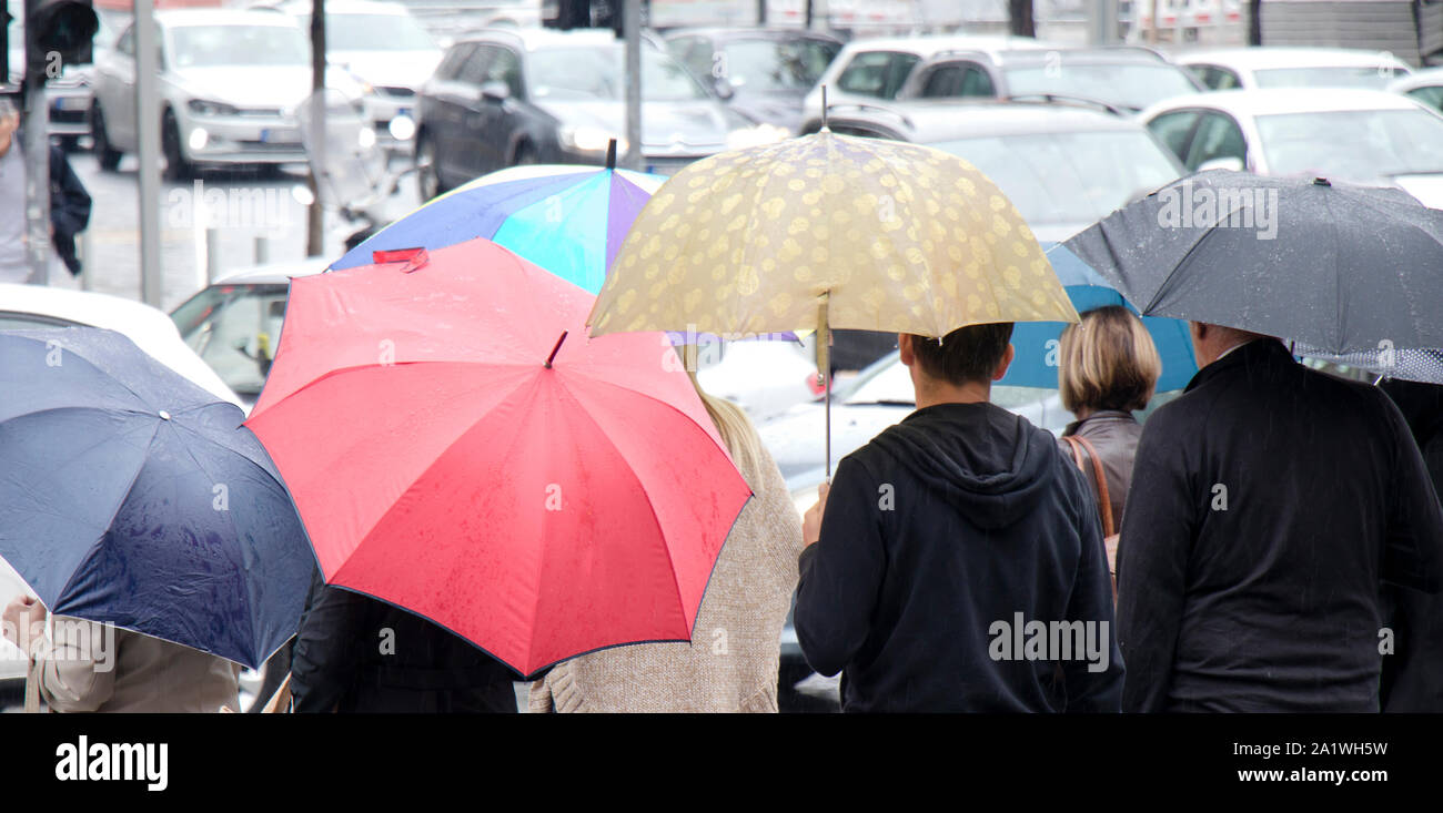 Belgrado, Serbia- Settembre 24, 2018: Le persone sotto gli ombrelloni in attesa alla strada pedonale incrocio in una trafficata strada piena di vetture in un giorno di pioggia a th Foto Stock