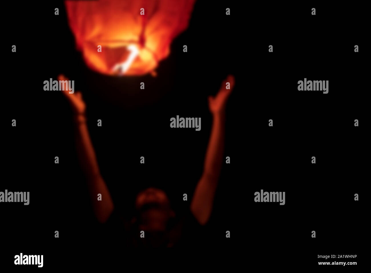 Abstract sfocata l'immagine di sfondo della persona del volo o il lancio di Red Sky lanterna di notte durante il Diwali, anno nuovo concetto di natale con spazio per tex Foto Stock