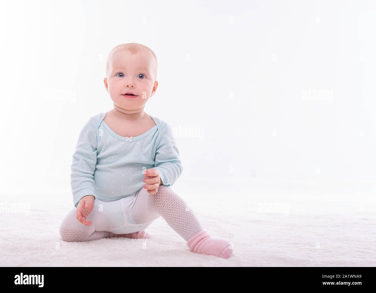 Bambina piccola su un tappeto bianco in una stanza luminosa. Foto Stock