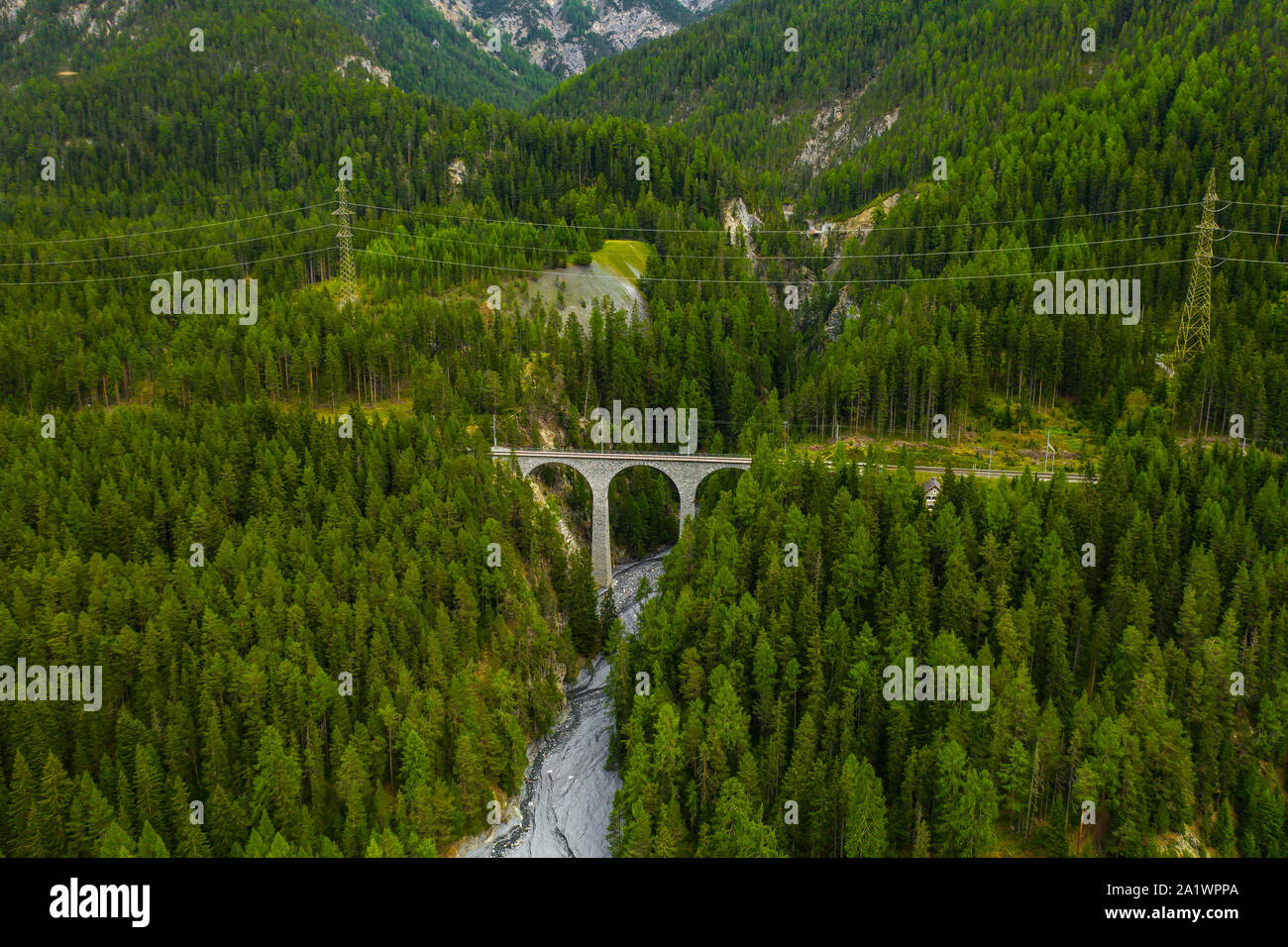 Inn fiume che scorre nella foresta in Svizzera. Vista aerea da fuco su un vecchio ponte ferroviario viadotto in montagna Foto Stock