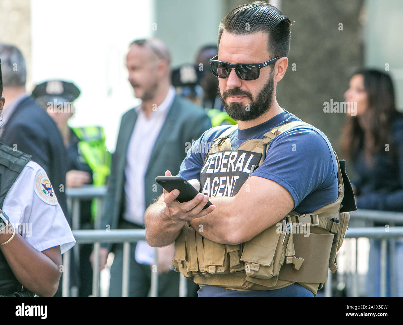 La città di New York, 9/27/2019: US agente federale sta verificando il suo telefono mentre in corrispondenza di una polizia checkpoint in Manhattan durante l Assemblea Generale delle Nazioni Unite. Foto Stock