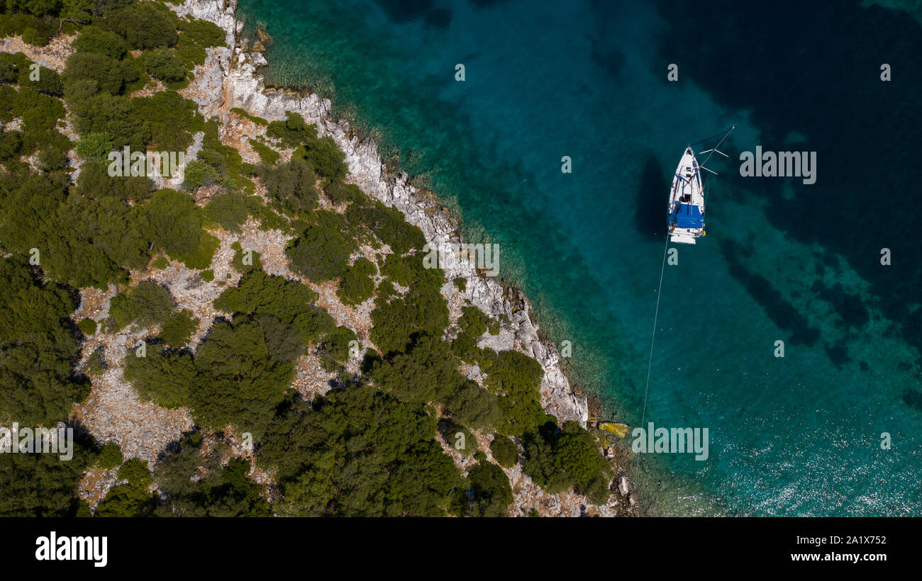 Foto aerea di uno yacht a vela all'ancora in una costa protetta greca nel mare blu chiaro Estate Mediterraneo Foto Stock