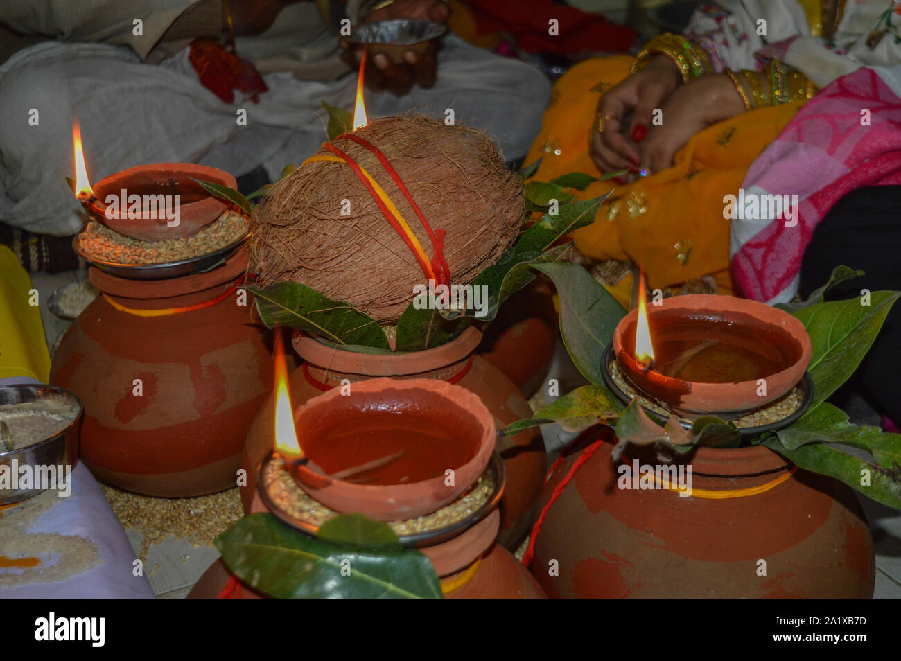 Pentola di creta con noce di cocco, il Mango Tree foglia, olio di riso, frumento illuminato per il culto del dio indiano. Foto Stock