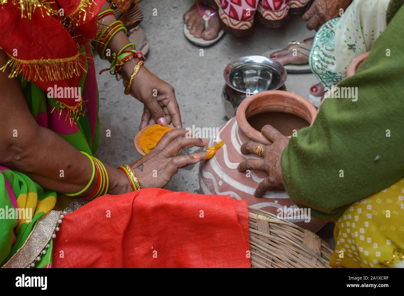 Signora mettendo la curcuma sulla pentola di creta in matrimoni indiani. Foto Stock