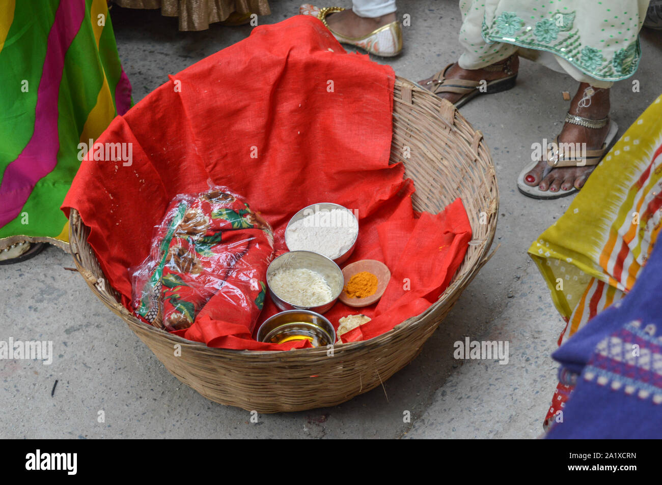 Una cesta caricata con la curcuma, riso, pavimento, l'olio di senape, panno rosso in matrimonio indiano. Foto Stock