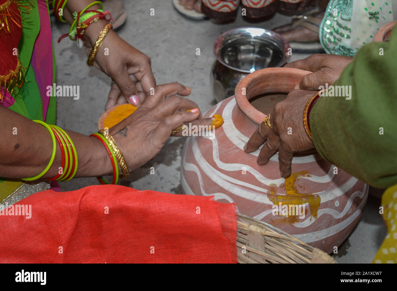 Signora mettendo la curcuma sulla pentola di creta in matrimoni indiani. Foto Stock