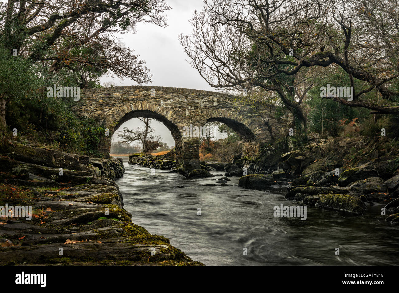 L'antico ponte Weir del XVII secolo e il torrente al Meeting of the Waters nel Killarney National Park, County Kerry, Irlanda Foto Stock