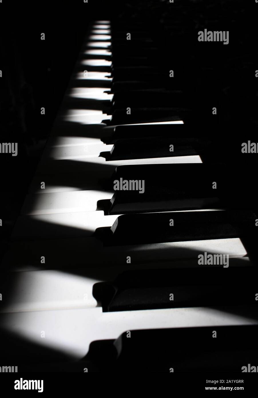 Tastiera di pianoforte sotto luce diagonale con ombre Foto Stock